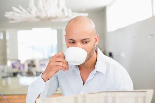 Seorang pria minum kopi sambil membaca koran di rumah — Stok Foto