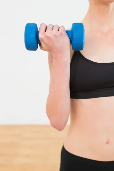 Mid section of a young woman exercising with dumbbell — Stock Photo, Image