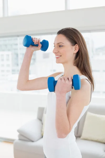 Fit woman exercising with dumbbells in fitness studio — Stock Photo, Image