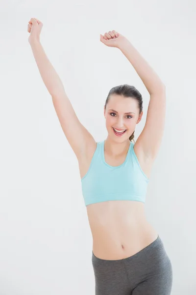 Smiling toned woman stretching hands against wall — Stock Photo, Image
