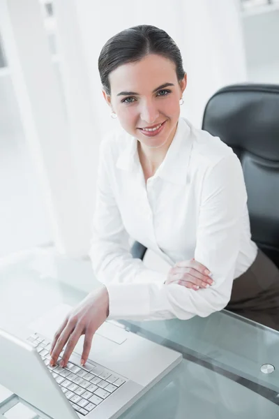 Mujer de negocios sonriente utilizando el ordenador portátil en el escritorio —  Fotos de Stock