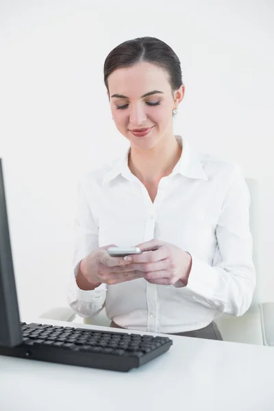 Businesswoman with mobile phone in front of computer — Stock Photo, Image