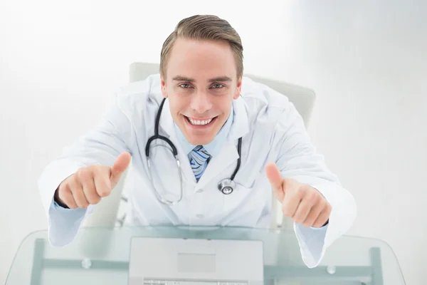 Retrato de arriba del médico sonriente con portátil haciendo gestos de pulgares hacia arriba —  Fotos de Stock