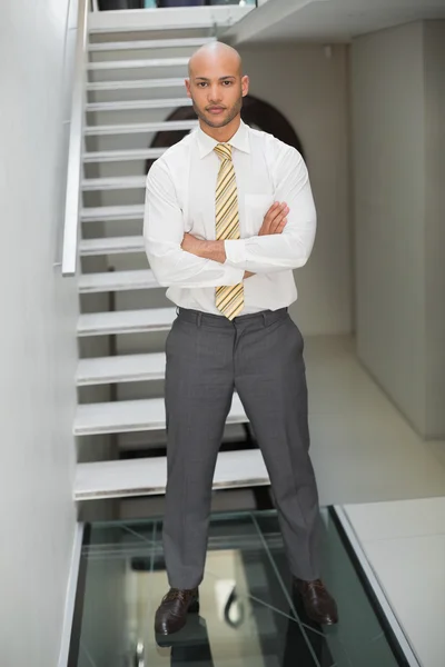 Hombre de negocios sonriente de pie contra la escalera —  Fotos de Stock