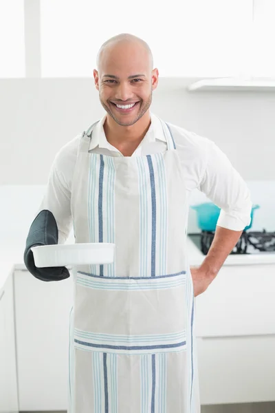 Uomo sorridente che tiene una teglia in cucina — Foto Stock