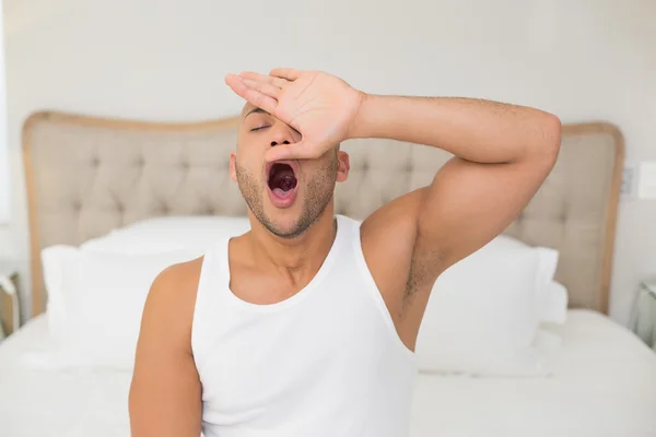 Joven bostezando en la cama — Foto de Stock