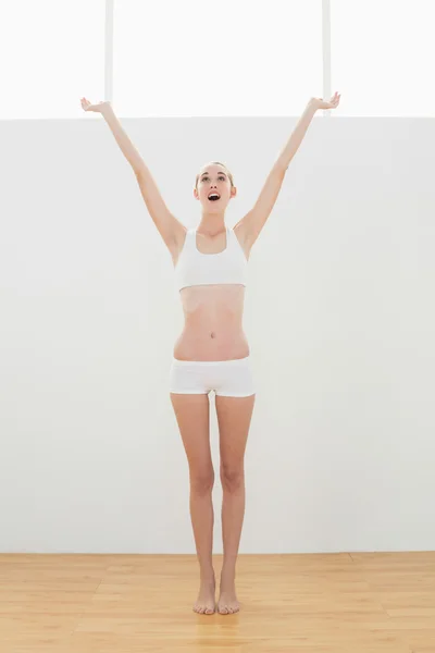Mulher apto alegre em sportswear esticando-se levantando os braços — Fotografia de Stock