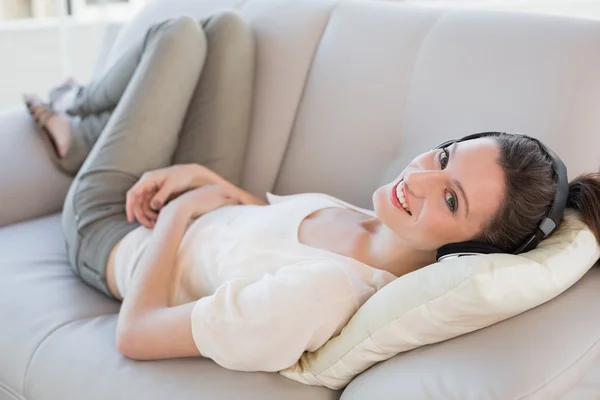 Relajada mujer joven casual disfrutando de la música en el sofá — Foto de Stock