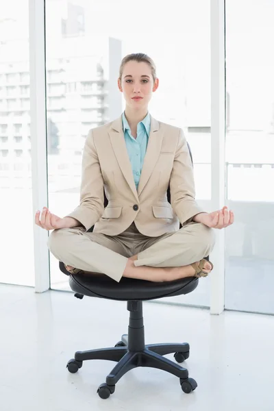 Focused chic businesswoman sitting in lotus position on her swivel chair — Stock Photo, Image