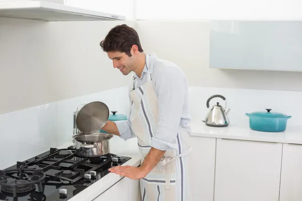 Jovem sorridente preparando comida na cozinha — Fotografia de Stock