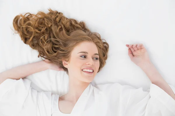 Blick von oben auf eine lächelnde junge Blondine im Bett — Stockfoto