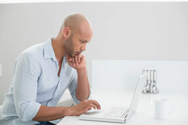Hombre casual concentrado usando el ordenador portátil en casa —  Fotos de Stock