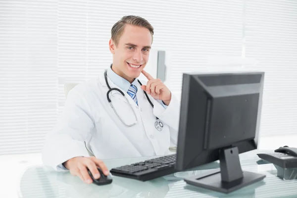 Sorridente medico di sesso maschile con computer presso lo studio medico — Foto Stock