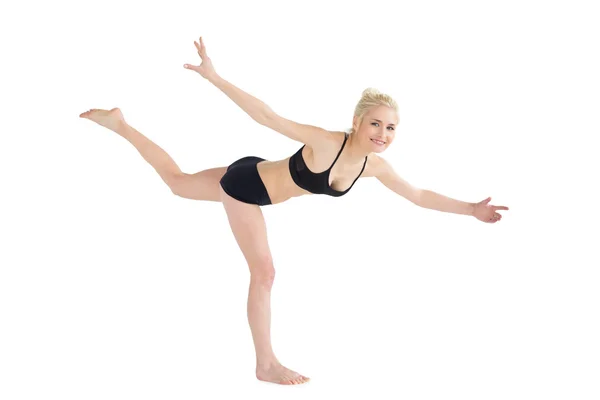 Full length of a sporty young woman balancing on one leg — Stock Photo, Image