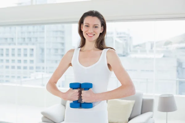 Fit woman exercising with dumbbells in fitness studio — Stock Photo, Image