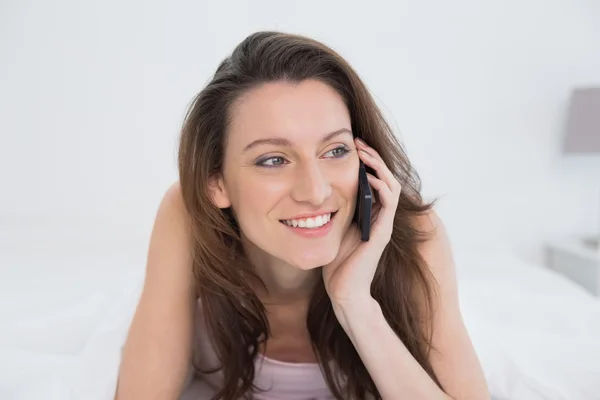 Bliska uśmiechający się kobiety przy użyciu telefonu komórkowego w łóżku — Zdjęcie stockowe