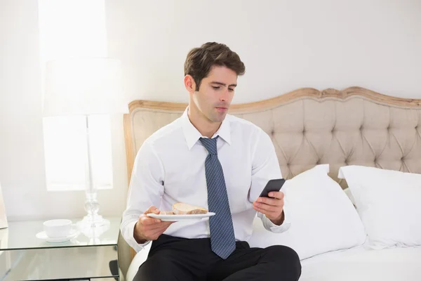 Hombre bien vestido mensajería de texto en la cama en casa —  Fotos de Stock