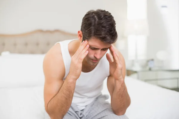 Молодой человек страдает от головной боли в постели — стоковое фото