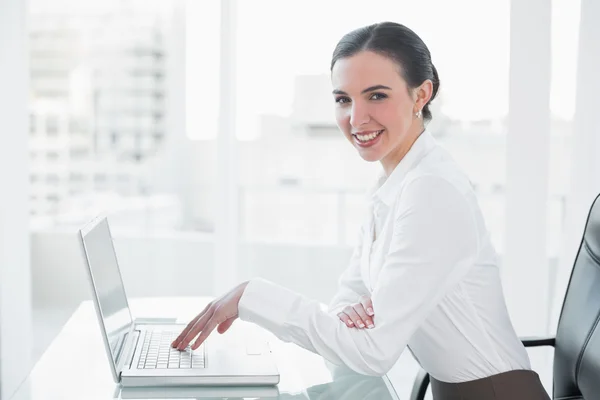 Mujer de negocios sonriente utilizando el ordenador portátil en el escritorio —  Fotos de Stock