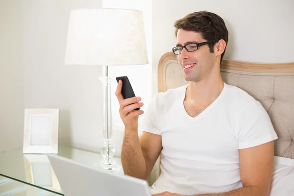 Casual sorrindo jovem mensagens de texto na cama — Fotografia de Stock