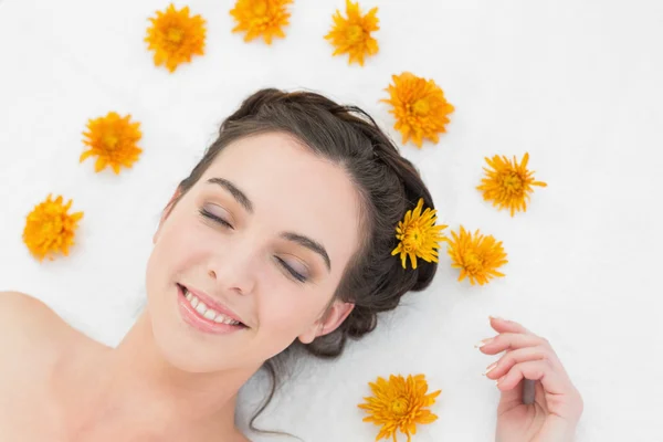 Schöne Frau mit geschlossenen Augen und Blumen im Schönheitssalon — Stockfoto