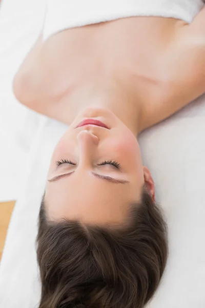 Jovem morena deitada na mesa de massagem com os olhos fechados — Fotografia de Stock