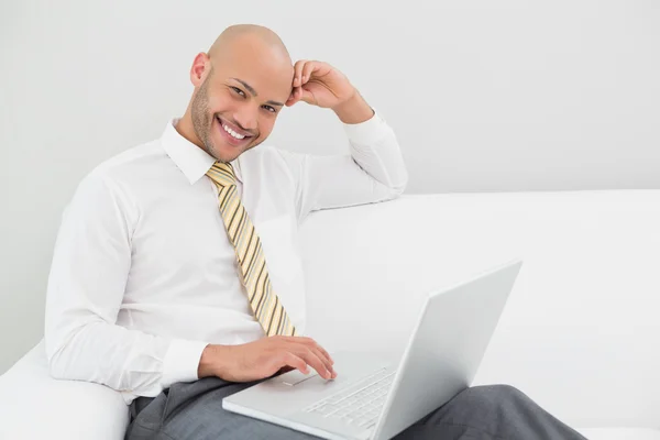 Χαμογελώντας επιχειρηματίας χρησιμοποιώντας φορητό υπολογιστή στον καναπέ στο σπίτι — Φωτογραφία Αρχείου