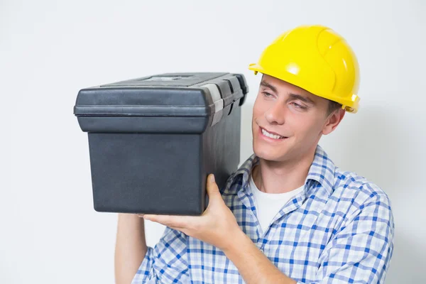 Smiling handyman in yellow hard hat carrying toolbox — Stock Photo, Image