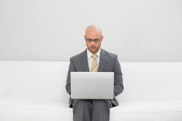 Businessman using laptop on sofa at home — Stock Photo, Image