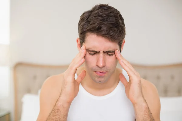 Joven sufre de dolor de cabeza en la cama — Stockfoto