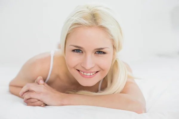 Närbild på en leende vacker blond i sängen — Stockfoto