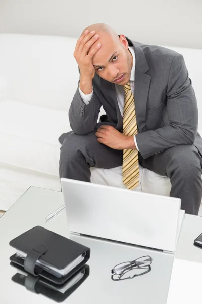 Bezorgd zakenman met laptop met hoofd in hand thuis — Stockfoto