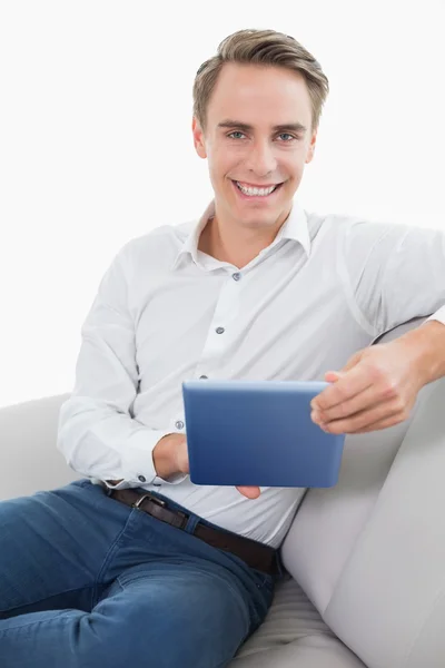 Jovem sorridente casual usando tablet digital no sofá — Fotografia de Stock