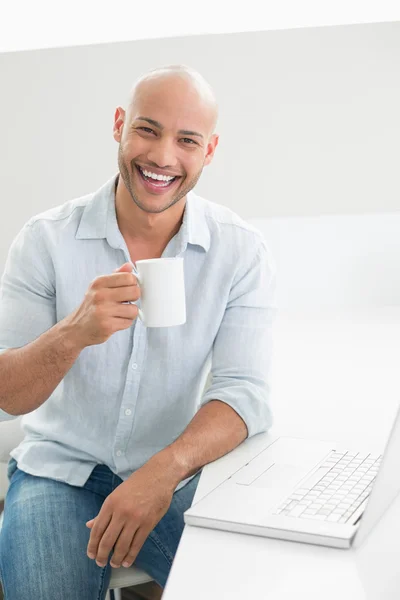 Sourire homme décontracté avec ordinateur portable boire du café à la maison — Photo