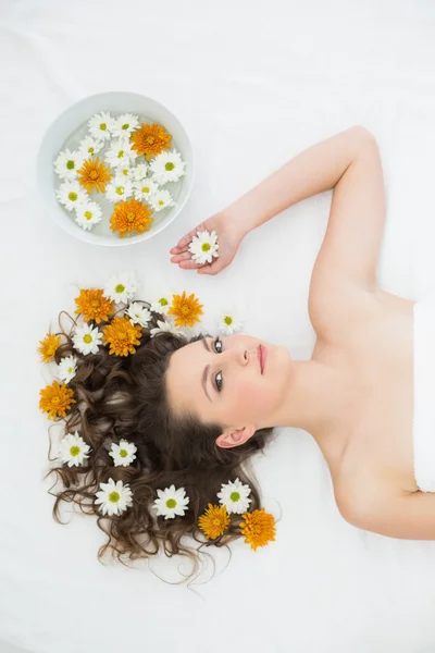 Piękna kobieta, leżąc z miski kwiatów w gabinecie kosmetycznym — Zdjęcie stockowe