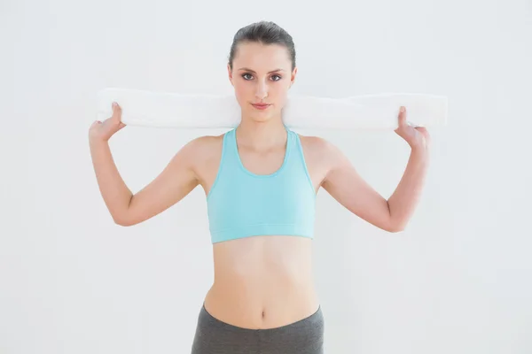 Ajuste mujer joven con toalla alrededor del cuello contra la pared — Foto de Stock