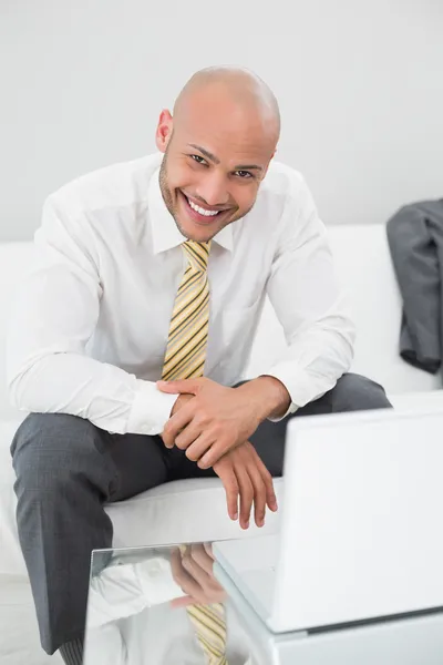 Hombre de negocios sonriente usando el ordenador portátil en el sofá en casa —  Fotos de Stock