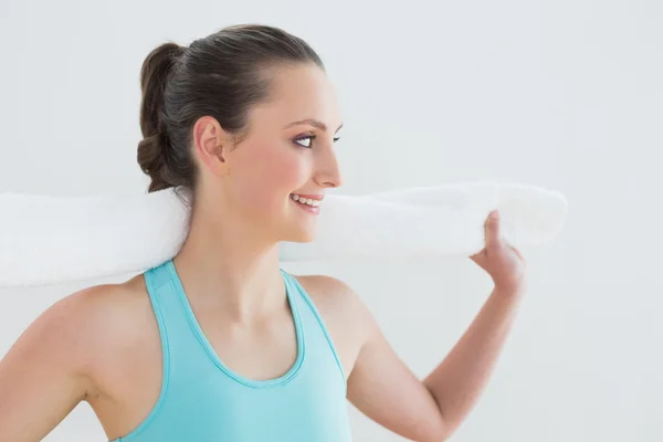 Fit woman with towel around neck against wall — Stock Photo, Image