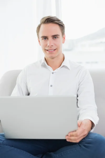 Portret van een toevallige jonge man met behulp van laptop op sofa — Stockfoto