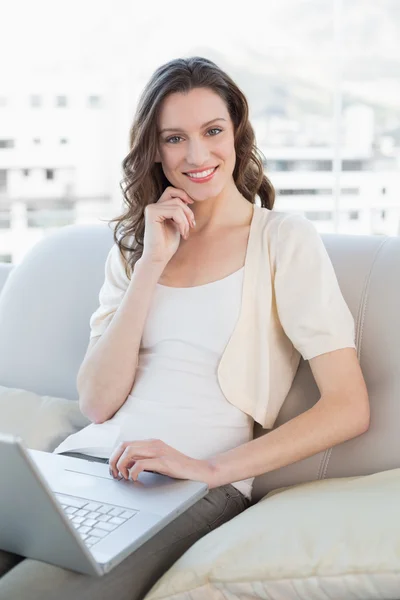 Portrait of a casual young woman using laptop on sofa — Stock Photo, Image