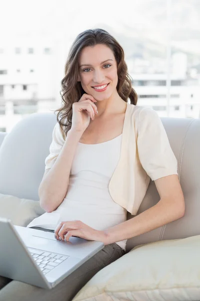 Portret van een toevallige jonge vrouw met laptop op sofa — Stockfoto