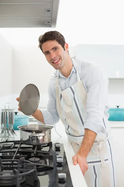 Smiling young man preparing food in kitchen — Stock Photo, Image