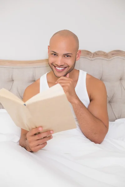 微笑轻松秃头的男人在床上读书 — 图库照片