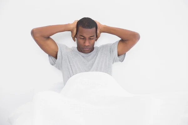 Sleepy Afro man covering ears with hands in bed — Stock Photo, Image