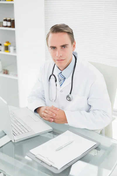 Улыбающийся врач-мужчина с ноутбуком в медицинском кабинете — стоковое фото