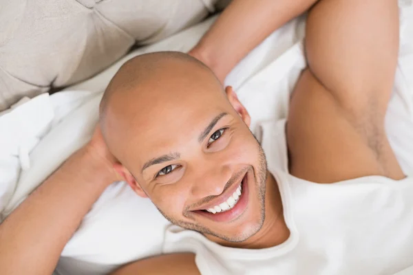 Primo piano di un giovane uomo calvo sorridente che riposa a letto — Foto Stock