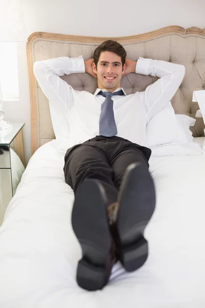 Rilassato sorridente uomo ben vestito sdraiato a letto — Foto Stock