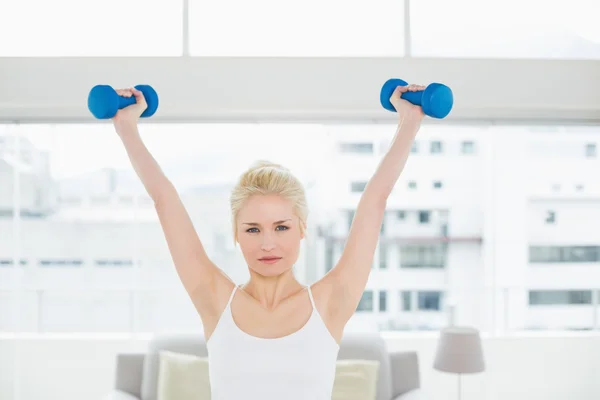 Mulher séria levantando halteres no estúdio de fitness — Fotografia de Stock