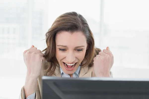 Businesswoman cheering with clenched fists at office desk — Stock Photo, Image