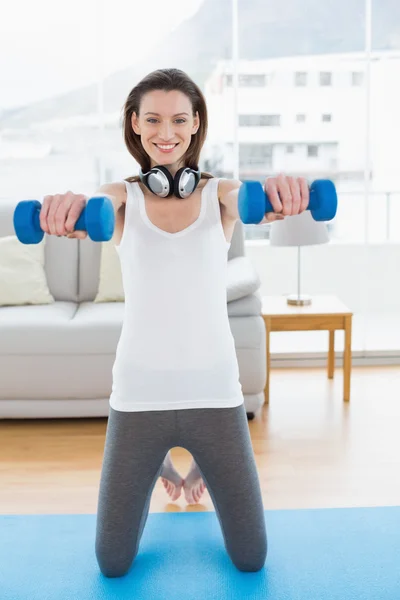 Fit woman exercising with dumbbells in fitness studio — Stock Photo, Image